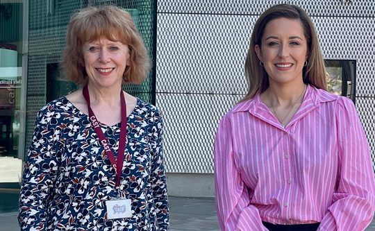 Director Deborah Rees and Sally Jameson MP stand smiling in front of the Cast Building