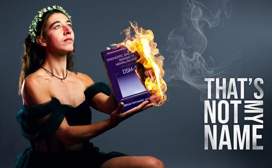 A woman with a flower crown holds a flaming DSM-5 book, expressing defiance. Text on the right reads "THAT'S NOT MY NAME" in bold letters.