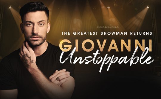The image features a man with a thoughtful expression, highlighted by dramatic stage lighting. Text reads "The Greatest Showman Returns, Giovanni Unstoppable."