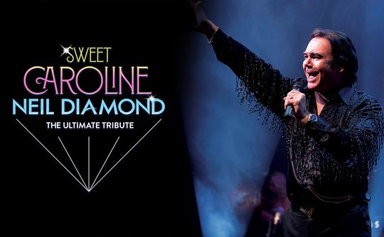 Man in fringed black shirt sings passionately into a microphone on stage, spotlight on him. Text on left reads "Sweet Caroline, Neil Diamond, The Ultimate Tribute."