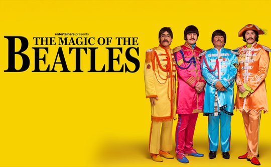 A quartet dressed in colourful, vintage-style military jackets with tassels stands against a vibrant yellow backdrop. Text reads "The Magic of The Beatles."