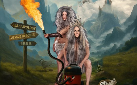 Two figures with wild gray hair pose in a surreal landscape. One holds a flame-thrower attached to a vacuum. Signs read “Sea of Apology,” “Passage to Power,” and “IKEA.” A castle looms in the misty mountains. A stray shoe and shopping cart are nearby, adding to the whimsical, dreamlike scene.