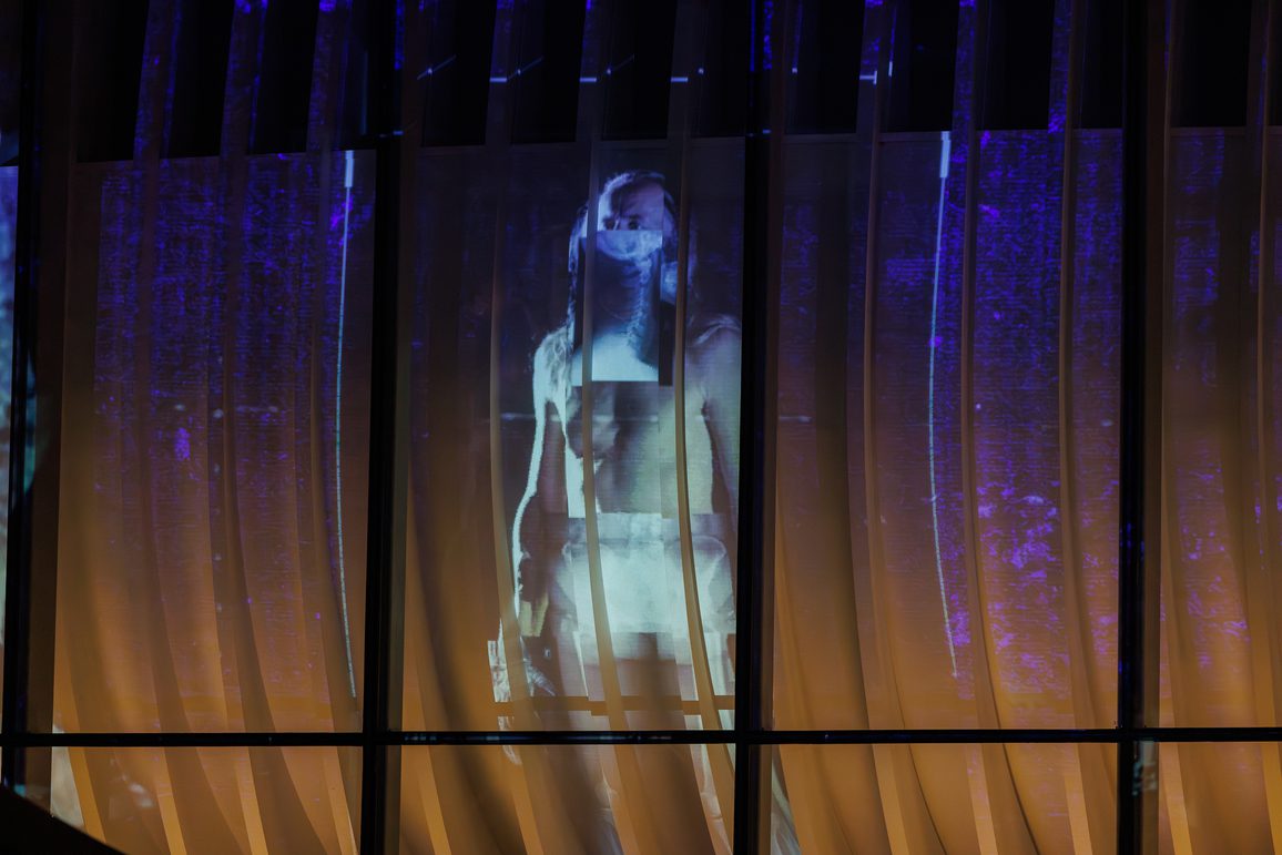 Projections onto a curved architectural feature of the theatre, Cast, in Doncaster. The projections are of a man created through a collage of images like a skeleton and different human shapes. The scene is from Lost Dream by Teatr Ósmego Dnia, at Cast in Doncaster.
