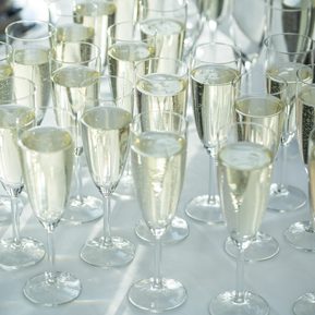 Champagne flutes on a white table cloth. Filled with a sparkling wine that bubbles in the glass.