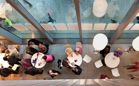 A shot taken from above, looking down on two pendant lights and people sat at tables drinking and chatting