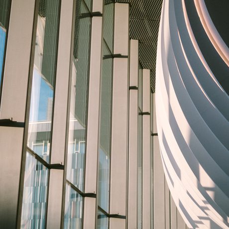 An artistic shot of the Cast foyer from a low angle, the curve of the building and the full height windows are the main feature, with the sky and council building in the distance