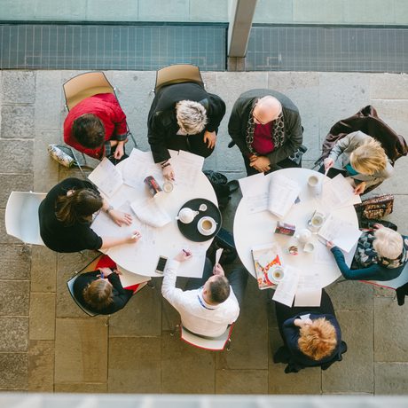 A shot taken from above, looking down on two pendant lights and people sat at tables drinking and chatting