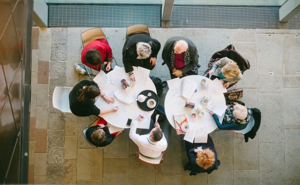 A shot taken from above, looking down on two pendant lights and people sat at tables drinking and chatting
