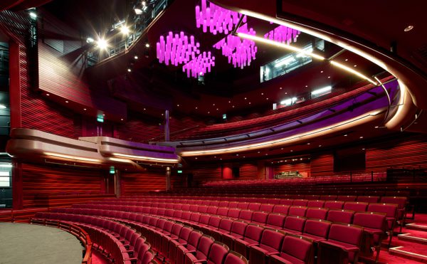 Interior of Cast's modern Main Space auditorium with curved rows of red seats, a spacious stage, and unique purple chandeliers, creating an elegant atmosphere.