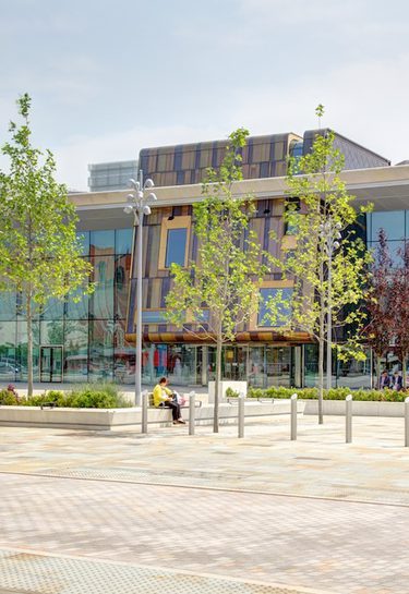 Cast building in the daytime, a wide angled shot across the square with green trees in the foreground